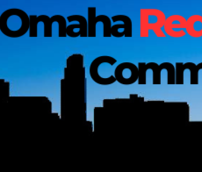 A city skyline silhouetted against a blue sky with the words "North Omaha Redlining Commission" above it