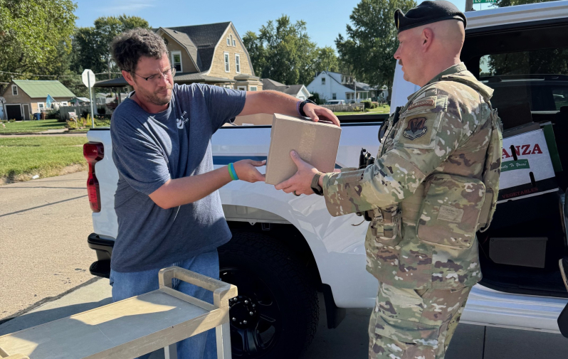 A volunteer helps a client load food into their truck.
