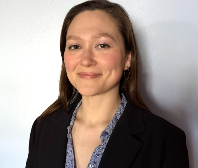 Headshot of a woman with brown hair wearing a purple button up shirt and black blazer