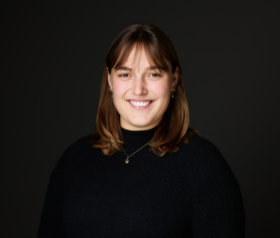 Headshot of a smiling woman with shoulder length brown hair and bangs wearing a black turtleneck